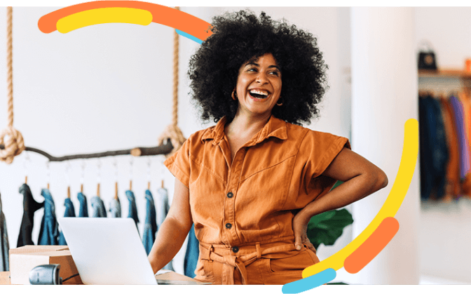 Foto de mujer afrocolombiana en su tienda de ropa, feliz porque recibió información sobre el crédito para cartera ordinaria de Bancolombia